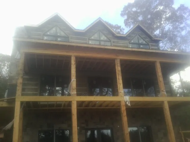 Dormers and porch framing on a large log home under construction — Roof Coating work by our crew in Mc Lean